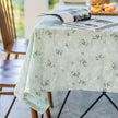 Floral patterned tablecloth on a table with a magazine underneath, outdoors.