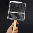 Hand holding a small grill with a yellow handle against a black background