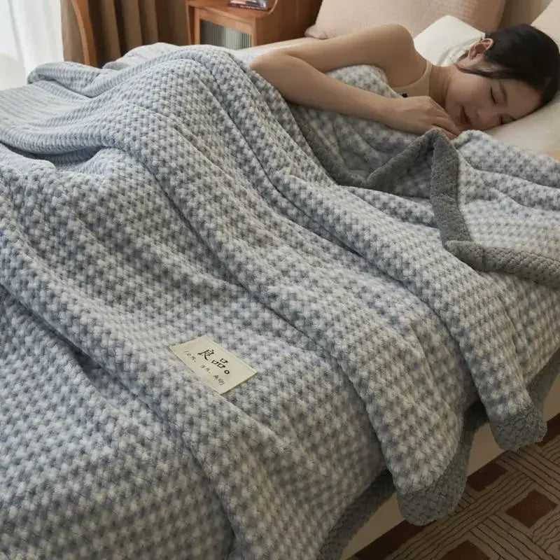 Person lying on a bed under a textured gray blanket with a visible brand label.