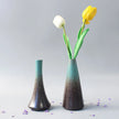 Two ceramic vases with gradient coloring holding tulips on a light gray background