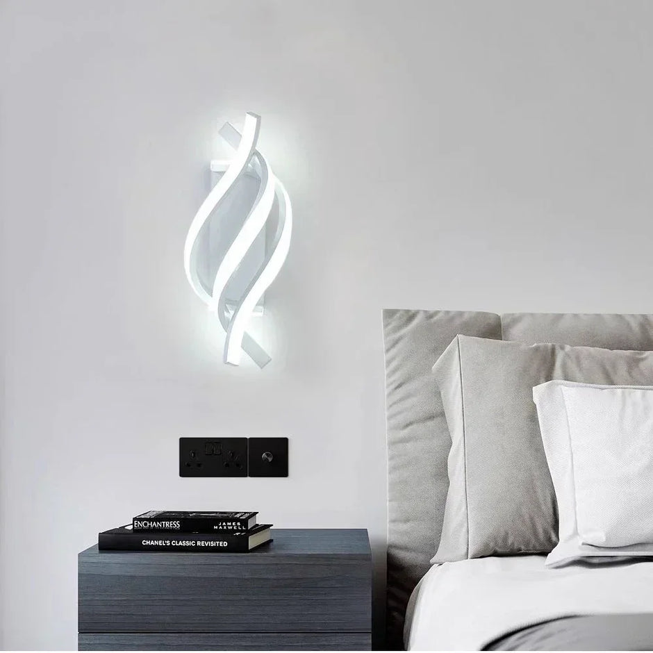 Modern wall sconce above a bed with books on a nightstand.