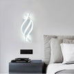 Modern wall sconce above a bed with books on a nightstand.