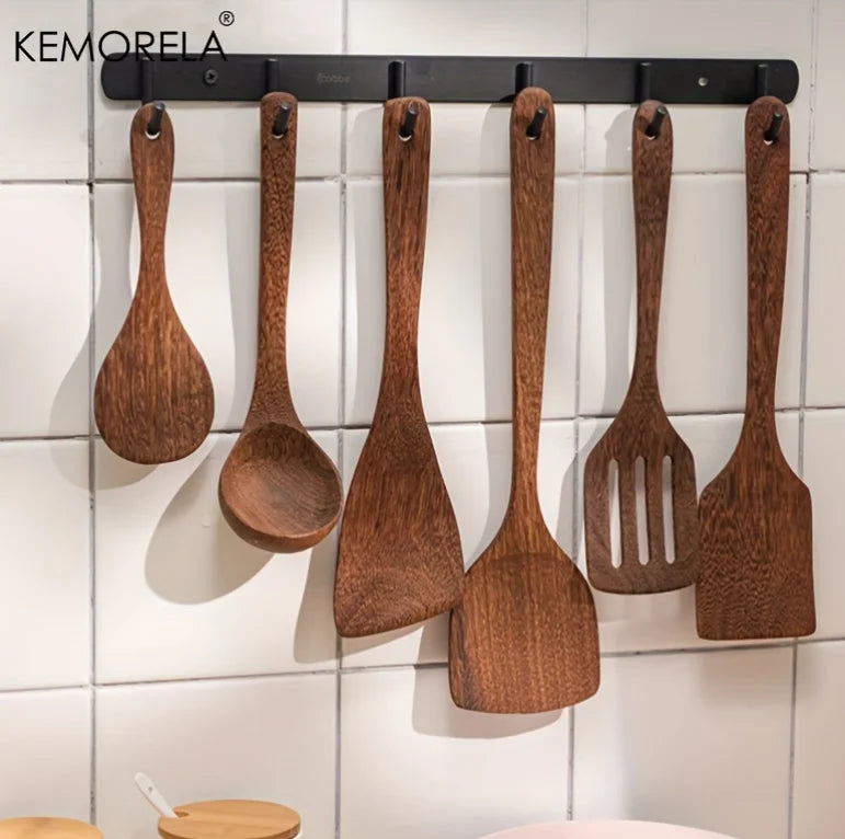 Set of wooden utensils hanging on a magnetic strip against a tiled wall.