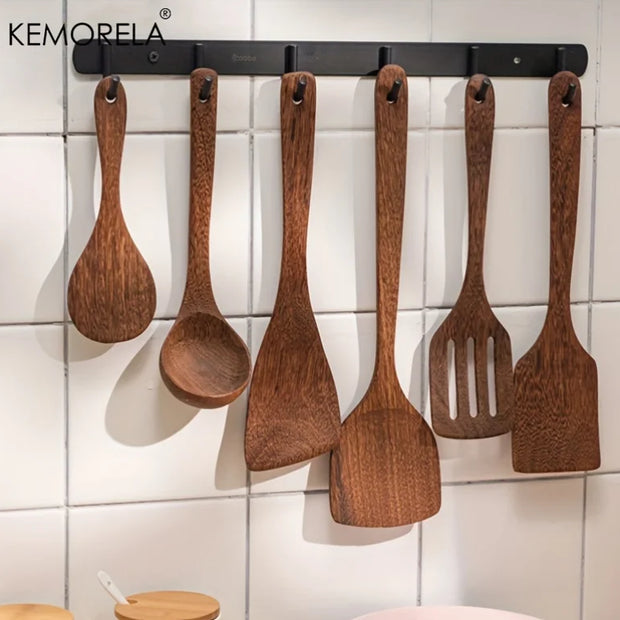 Set of wooden utensils hanging on a magnetic strip against a tiled wall.