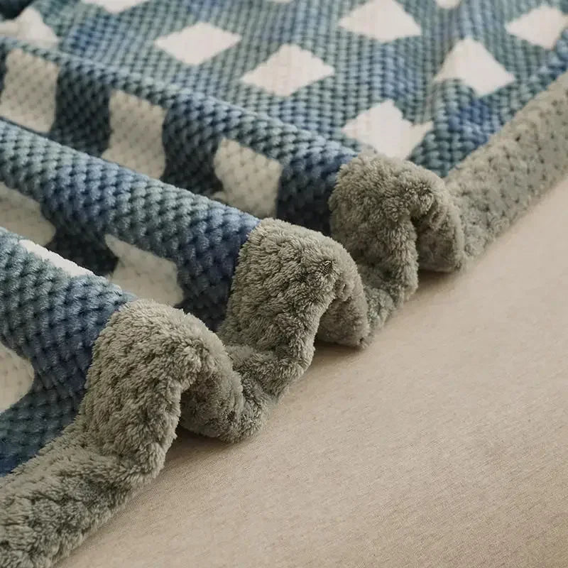 Close-up of a textured blanket with blue and gray pattern on a neutral background