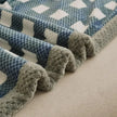 Close-up of a textured blanket with blue and gray pattern on a neutral background
