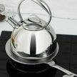 Stainless steel kettle on a stove with a white tiled wall in the background