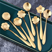 Set of gold floral spoons on a green tray with a gray background
