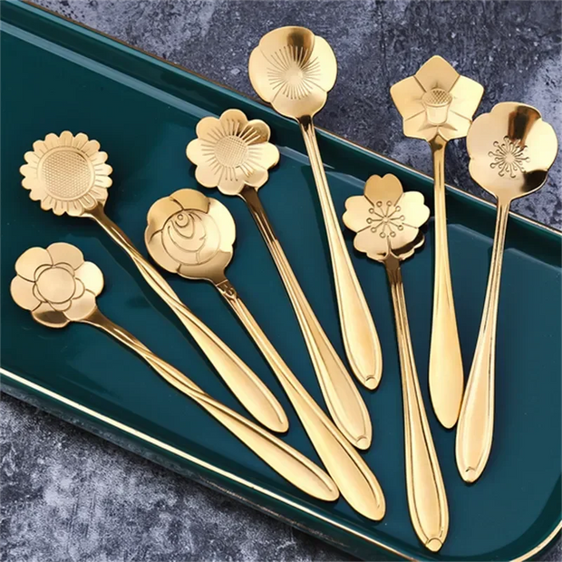 Set of gold floral spoons on a green tray with a gray background