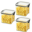 Three square storage containers with lids filled with yellow cereal on a white background