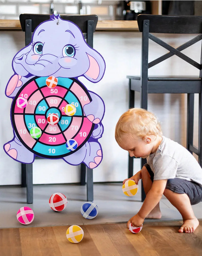 Child playing with a dartboard shaped like an elephant in a home setting