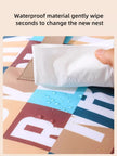 Hand using a white cloth to wipe a colorful surface with text about waterproof material.