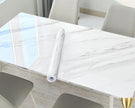 Roll of marble-patterned contact paper on a table with chairs in a room.