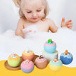 Child playing with colorful bath bombs featuring small figures in a bathtub filled with bubbles.