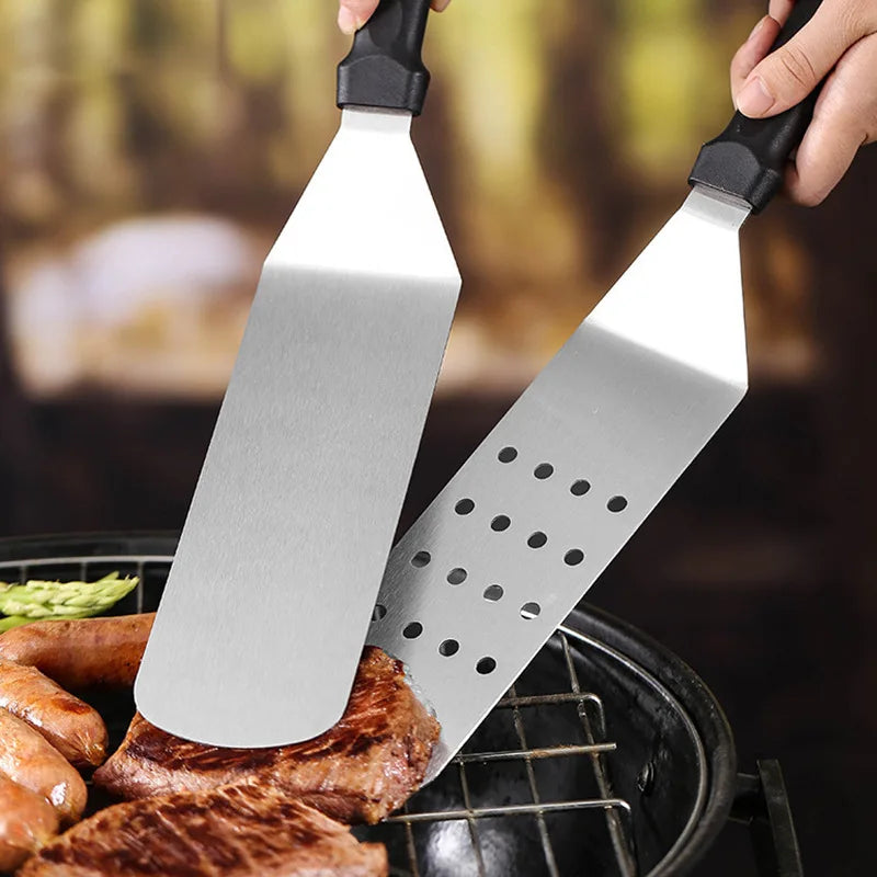 Two metal spatulas with black handles being used on a grill.