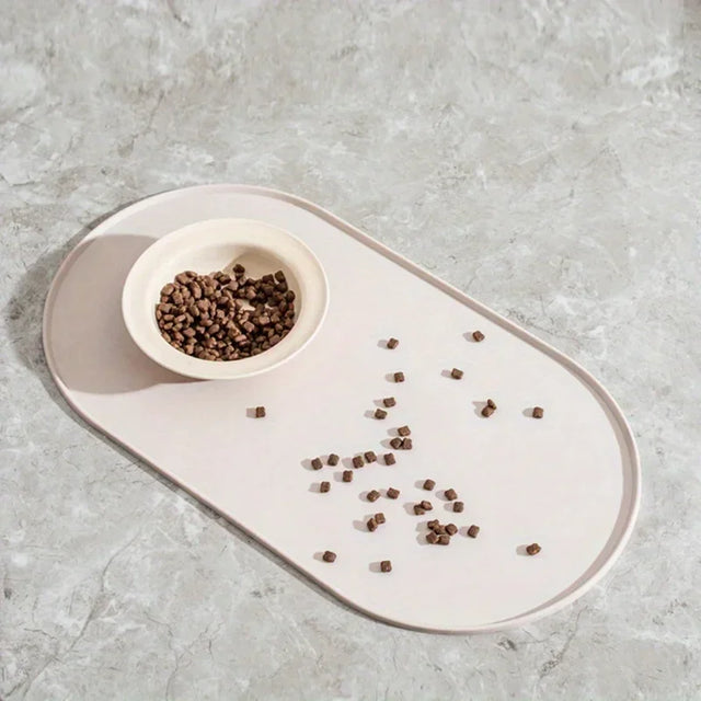 Cat food in a bowl on a tray with scattered food on a gray surface