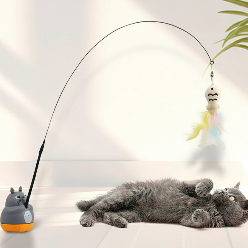 Cat playing with a toy on a white surface with a plant in the background