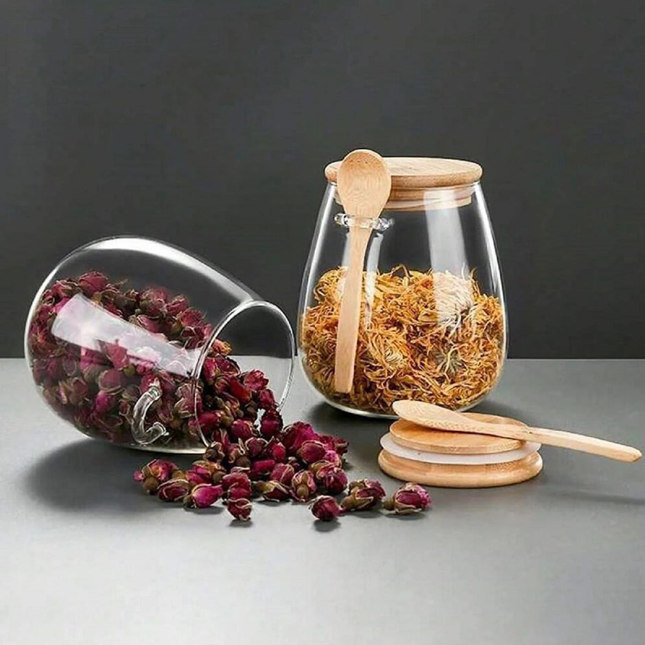 Glass jars with wooden spoons and dried herbs on a gray surface