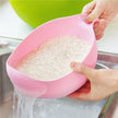 Person using a pink colander to drain water from rice in a kitchen sink.