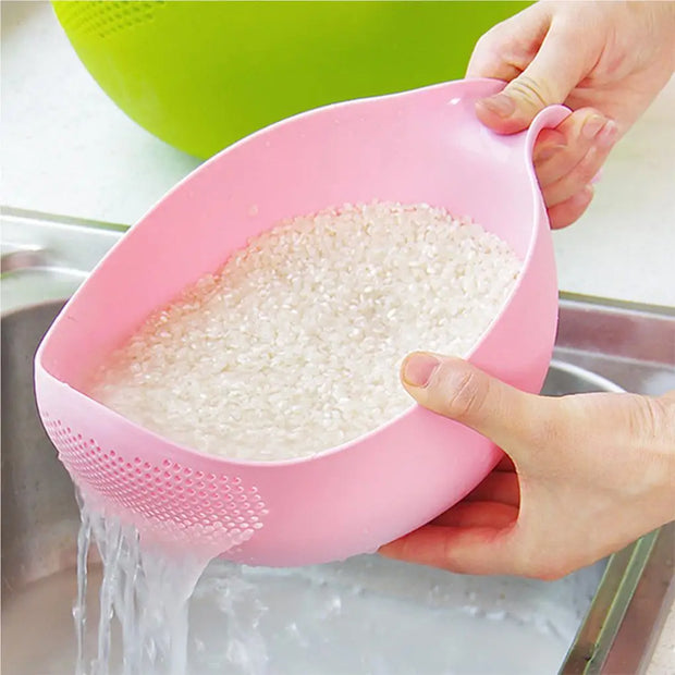 Person using a pink colander to drain water from rice in a kitchen sink.