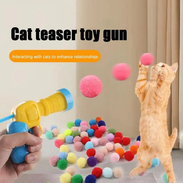 Cat teaser toy gun with colorful balls and a cat interacting with it.