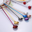 Set of colorful spoons on a white surface with a magazine underneath.