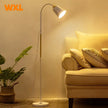 Floor lamp next to a beige sofa with pillows in a cozy living room setting.