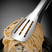 Metallic slotted spoon lifting spaghetti from a bowl