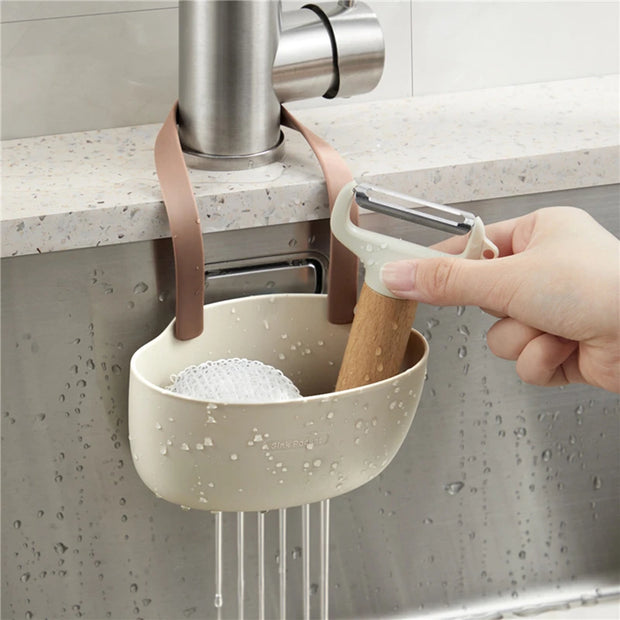 Kitchen sink caddy with sponge and peeler hanging over a faucet
