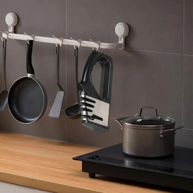 Kitchen utensils and pots hanging on a rack against a tiled wall.