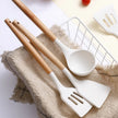 White kitchen utensils with wooden handles on a textured surface