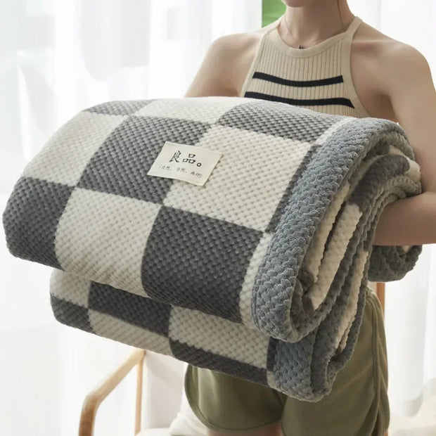 Person holding a checkered blanket with a visible brand label against a white curtain background