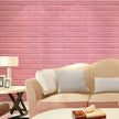 Pink brick-patterned wall with a beige sofa and decor items.