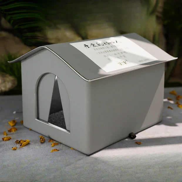 White pet house with a transparent door on a gray surface with dried leaves.