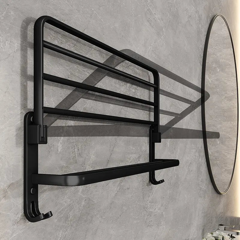 Black towel rack mounted on a gray tiled wall with a round mirror to the right.