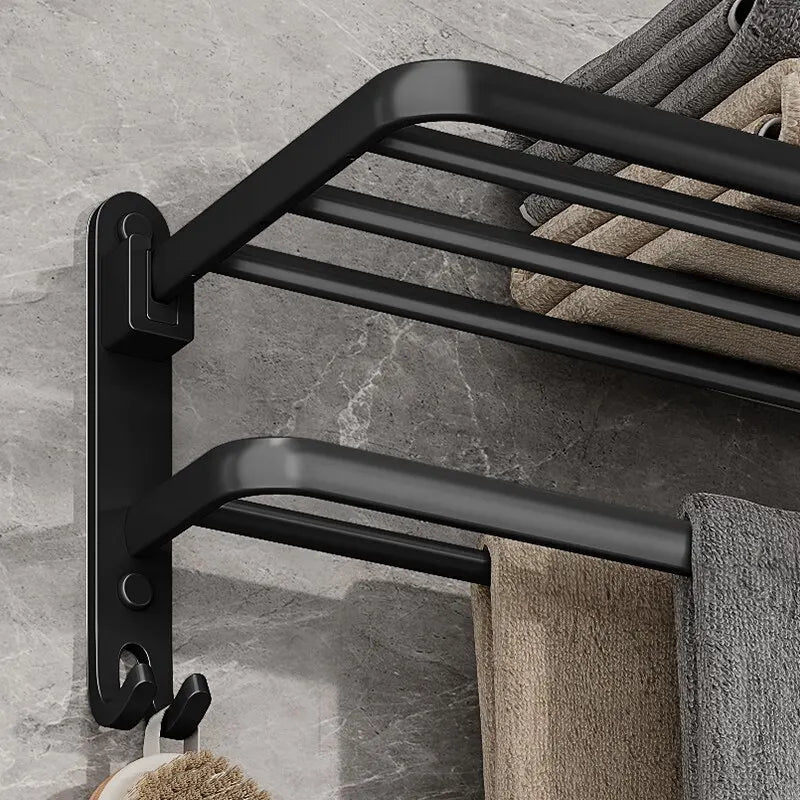 Black towel rack mounted on a gray tiled wall with towels hanging from it.