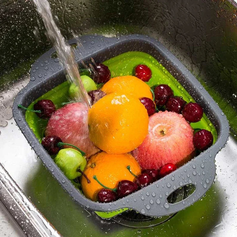 Collapsible fruit and vegetable sink basket with fruits being washed under running water.