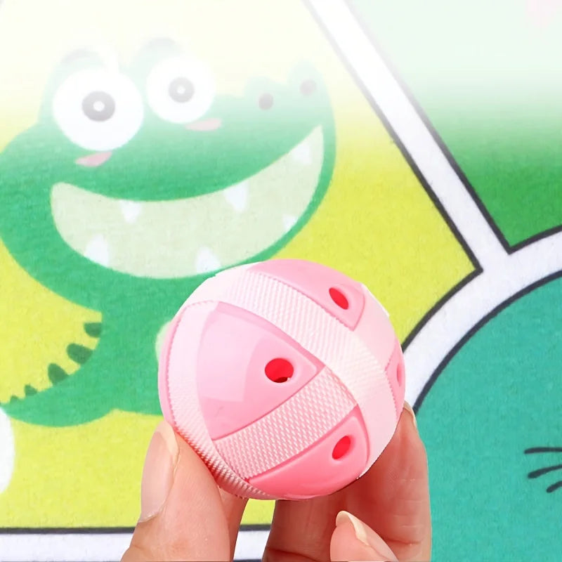 Pink toy ball held by a hand with a cartoon dinosaur in the background