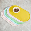 Set of colorful pet bowls with a yellow one containing food on a gray surface