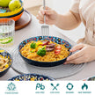 Person holding a bowl of spaghetti with colorful plates and glasses on a table, featuring the Vancasso brand.