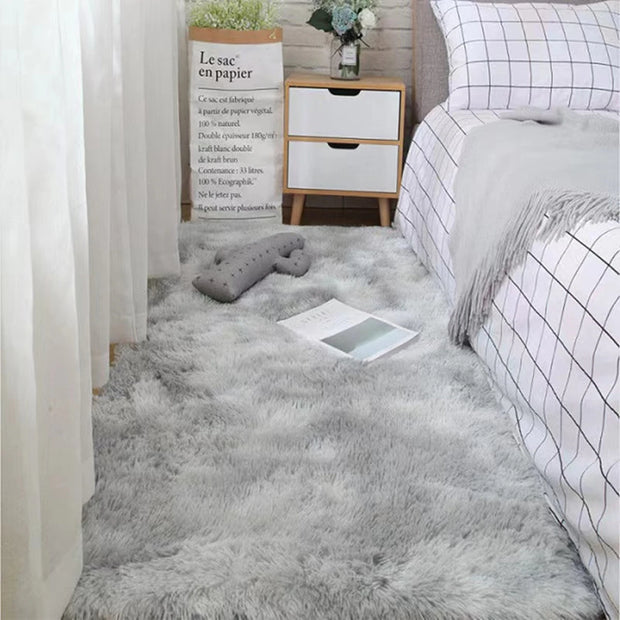 Gray fluffy rug in a bedroom with a bed, nightstand, and decorative items.