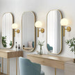 Modern vanity setup with three wall mirrors and gold sconces in a room.
