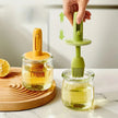 Two silicone scrubbers, one yellow and one green, being used to clean jars on a marble surface.