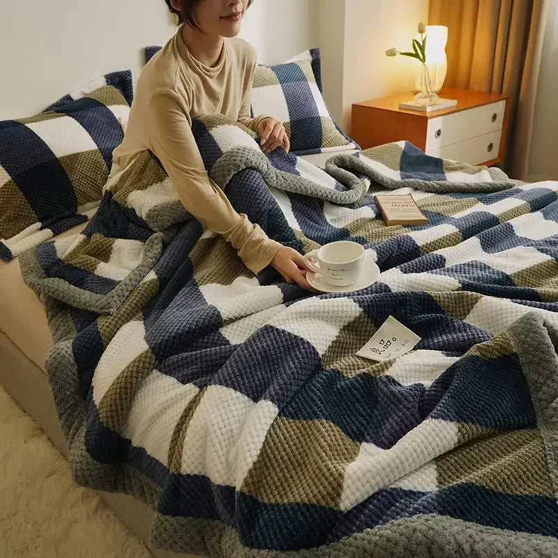 Person sitting on a bed with a patterned blanket, holding a cup.