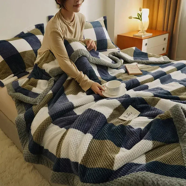 Person sitting on a bed with a patterned blanket, holding a cup.