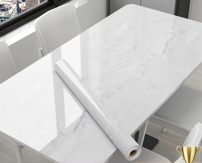 Roll of marble-patterned vinyl wrap on a table with chairs in the background