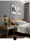 Modern bedroom with wooden bed and side table, gray walls, and decorative elements.