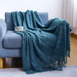 Teal blanket draped over a blue armchair with a white cup on a saucer.