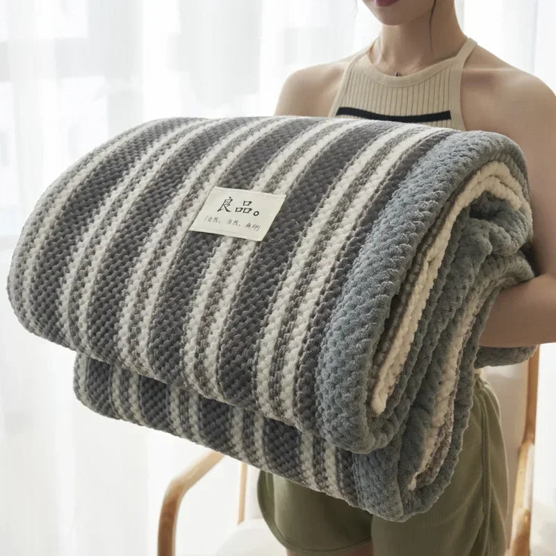 Person holding a striped blanket with a visible brand label against a light background