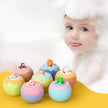 Colorful bath bombs with cartoon characters on a yellow surface, with a child in the background.